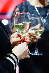 A glass of white wine or champagne in a woman's hand.