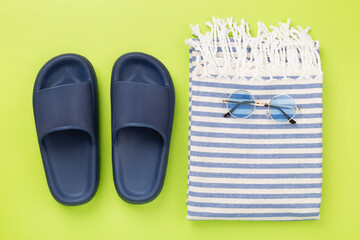 Beach towel with summer accessories on color background, top view