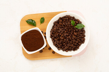 Roasted coffee beans with leaves on concrete background,top view