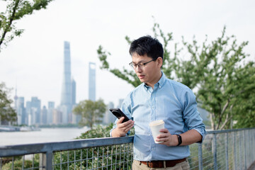 Fototapeta premium asian businessman using smart phone while having coffee