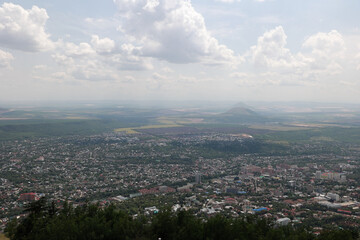 Panoramic Aerial View Of The City Of Pyatigorsk, Russia, Sprawling Below Mount Mashuk. Surrounding Hills And Fields Under A Cloudy Summer Sky. Caucasus Region.