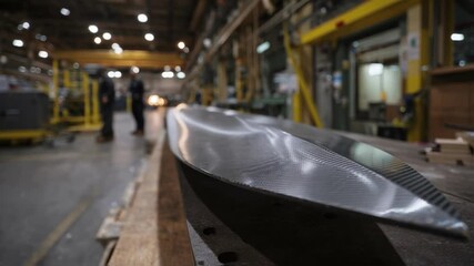 A side profile of a windturbine blade in the final stages of fabrication with carbonfiber strands visibly adhered to its surface demonstrating the lightweight yet strong qualities essential