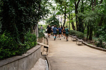 Fototapeta premium Urban running club community in colorful activewear jogging together across pedestrian areas, bridges, and parks. Anonymous group of runners in a vibrant city setting