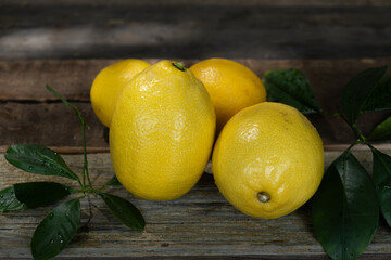 Lemons with fresh leaves on rustic background