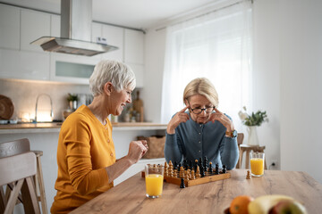 Senior women playing chess and having fun at home