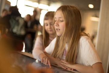 Girl uses touchscreen device for educational purposes, engaging with digital learning materials. Modern technology supports early childhood development through interactive and intuitive tools.