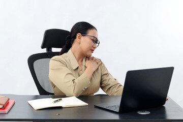 Unhappy female working in the office sitting on office desk while using laptop computer, front...