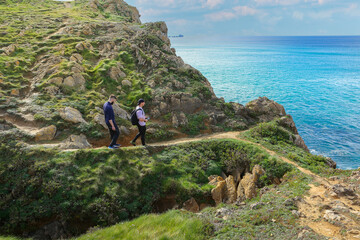 Two people walking through the landscape of the Costa Quebrada in Cantabria