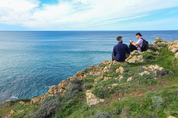Two people walking through the landscape of the Costa Quebrada in Cantabria