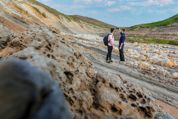 Two people walking through the landscape of the Costa Quebrada in Cantabria