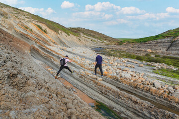 Two people walking through the landscape of the Costa Quebrada in Cantabria