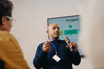 Plakat Businessman presenting project scope using a microphone during a formal meeting