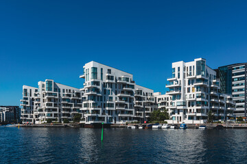 Obraz premium Moderne Wohngebäude am Wasser unter blauem Himmel.