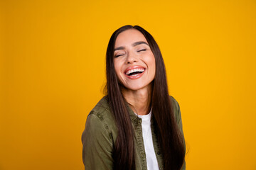 Happy young woman laughing joyfully in casual style on a vibrant yellow background, showcasing...