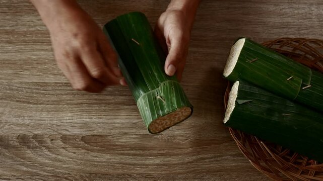 a man's hand unwrapped raw tempeh indonesia traditional food