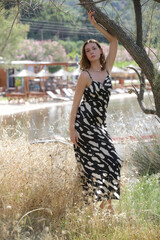 Summer outdoor fashion portrait of female model in elegant silk black and white dres in the park