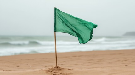 Single beach flag captured from a low angle on the sand, waves blurred in the distance with clear sea green tint