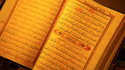 Close up of open Holy Quran with elegant Arabic calligraphy under warm lighting showcasing Islamic...