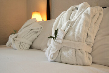 Two folded bathrobes on bed in hotel	
