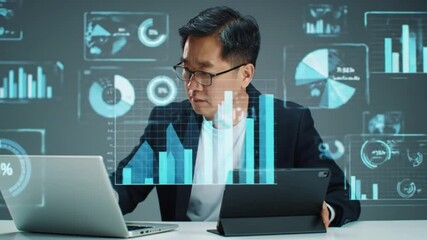 Businessman analyzes data on laptop and tablet reviewing financial charts and graphs displayed as a digital overlay - Powered by Adobe
