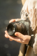 woman traveler holds a camera in her hands while standing on the shore of the mountain lake. Close up