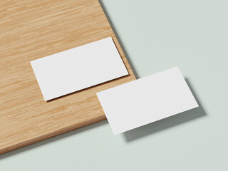 A pair of white business cards lying on a wooden table, with a subtle shadow highlighting their minimalist design.