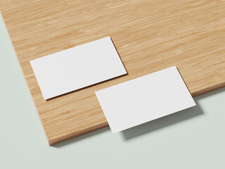 Two white business cards placed on a wooden background, with soft shadows adding depth to the clean, modern design.