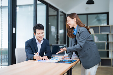 Two asian businesspeople discussing and working together with marketing data documents at office, businesspeople discussing and reviewing documents at meeting