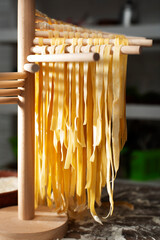 Homemade noodles hanging on wooden noodle dryer rack. Home cooking concept