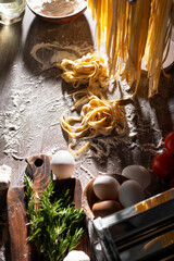 Homemade noodles hanging on wooden dryer rack over messy kitchen table background high angle top view