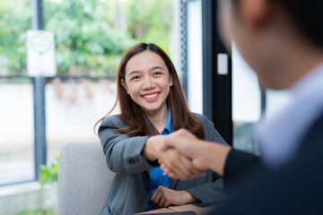 Two business people shaking hands during a meeting in a modern office, concluding a successful deal...