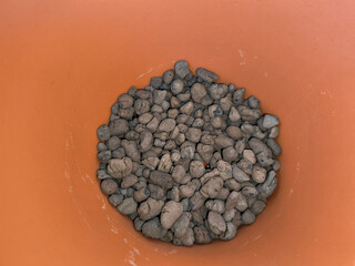 Clay pebbles filling the bottom of a terracotta pot for drainage copy space