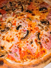 Delicious pizza with ham and mushrooms baking in oven