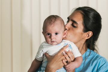 Nurse kissing five month old baby during physiotherapy session