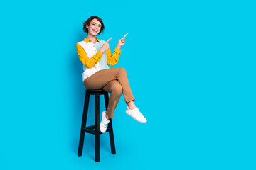 Photo of positive girl trader sitting stool demonstrate sale discount isolated blue color background