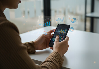 A woman uses her smartphone to analyze financial data charts and graphs displayed on a holographic screen modern technology business concept showcasing mobile analytics and data visualization