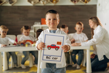 Front view of boy that is standing. Children in kindergarten with their teacher