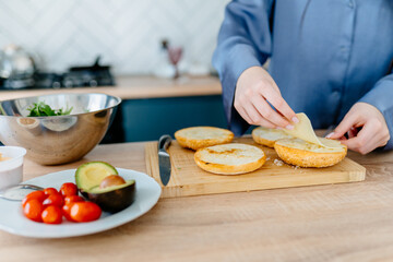 Teenage girl preparing breakfast sandwich with cheese