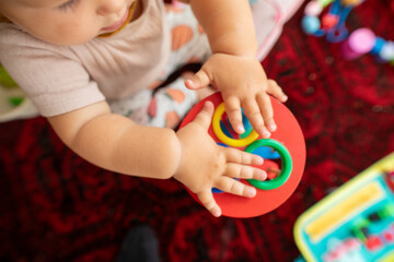 Adorable baby's hands playing with a colorful stacking ring toy. Perfect for developmental milestones and educational content.