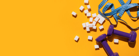White sugar cubes, purple dumbbells, measuring tape on yellow background flat lay top view. Concept of sweets consumption and addiction, global health and excess weight issue, sugar-free diet, sports 