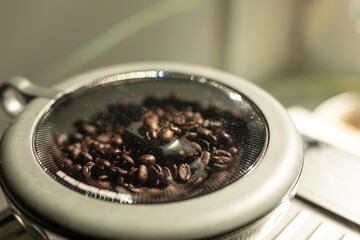 Roasted coffee beans in a transparent grinder container, ready for brewing. Rich aroma and fresh...