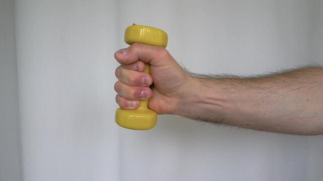 Sports fitness for gym Yellow Dumbbell 1 kg vinyl in hand of person on white background. Slow motion