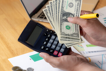 Partial view of hands using a calculator and writing down expenses, concept of personal finance management