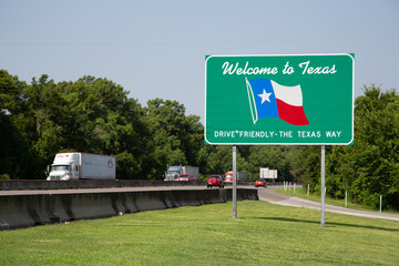 Texas state highway welcome sign with trucks driving by. Perfect for travel, transportation, and Texas-themed projects.