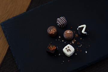 Handmade chocolates on a dark plate on the table