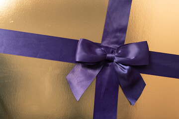 Luxury gift wrapping, purple ribbon and bow on gold background. Perfect for holidays or special...