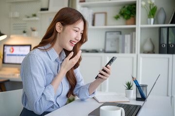 Obraz premium Cheerful young female professional enjoying a virtual meeting on her phone during remote work.