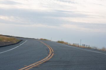 A scenic photo of an empty road curving gently under a cloudy sky. Perfect for travel or adventure themes.