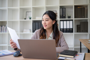 Young executive multitasking between paperwork and digital tasks in a clean, organized office.