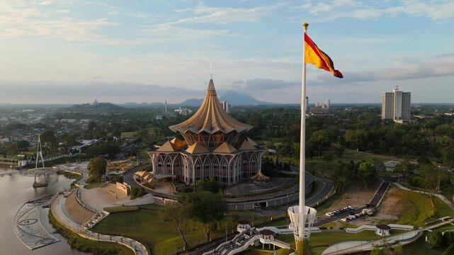 Drone view from behind the Sarawak State Assembly building DUN, showcasing its intricate architecture and prominent flagpole with the Sarawak flag flying at full height.
